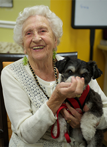 a woman holding a small dog and smiling